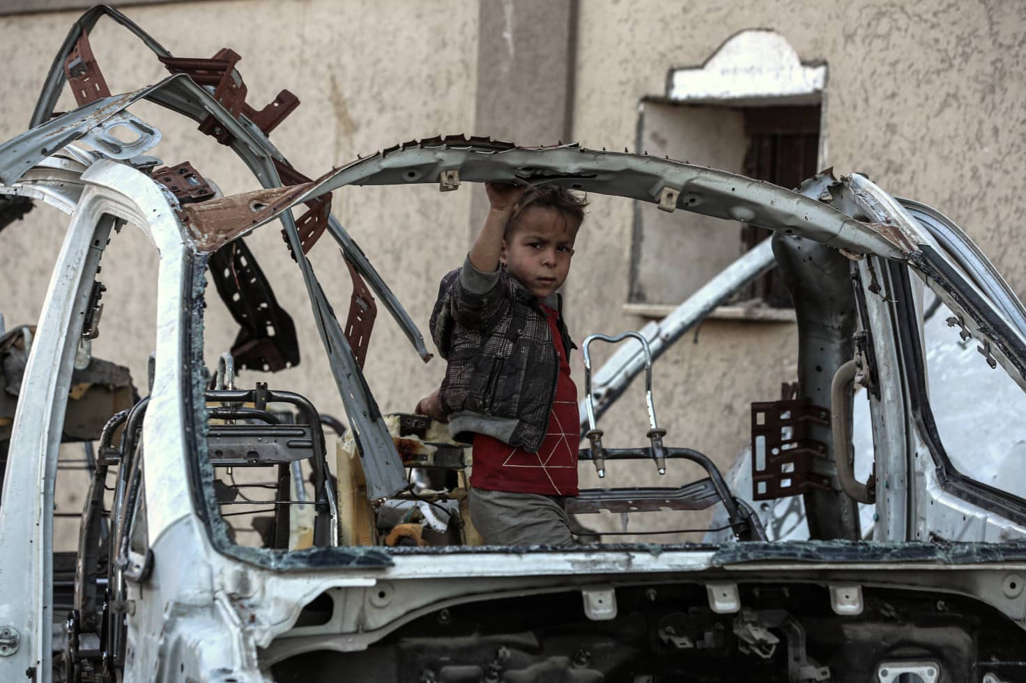 Un niño mira a cámara entre restos de un coche